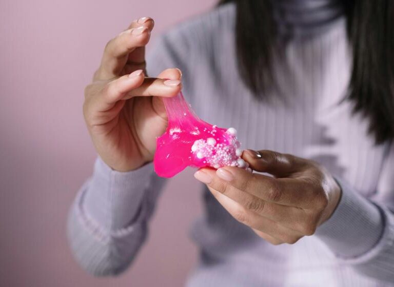 Pink color slime in hands on a girl