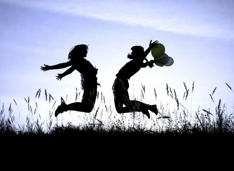 Silhouette of two friends jumping up.
